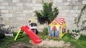 A children's play area with a red slide, a small playhouse, and a water fountain.