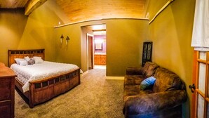 Un dormitorio con una cama de madera, un sofá de cuero marrón y un aparador de madera.