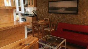 Un ambiente compatto con angolo cottura, zona pranzo e un divano rosso.