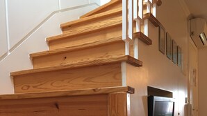 Una scala in legno dal design lineare che conduce a un'area d'appoggio con un televisore a parete.