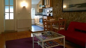 Un ambiente compatto con angolo cottura, zona pranzo e un divano rosso.