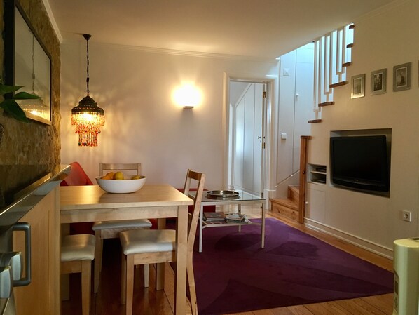 A modern living room with a dining area, a staircase, and a mounted TV. - 4 Flores (Lisbon)