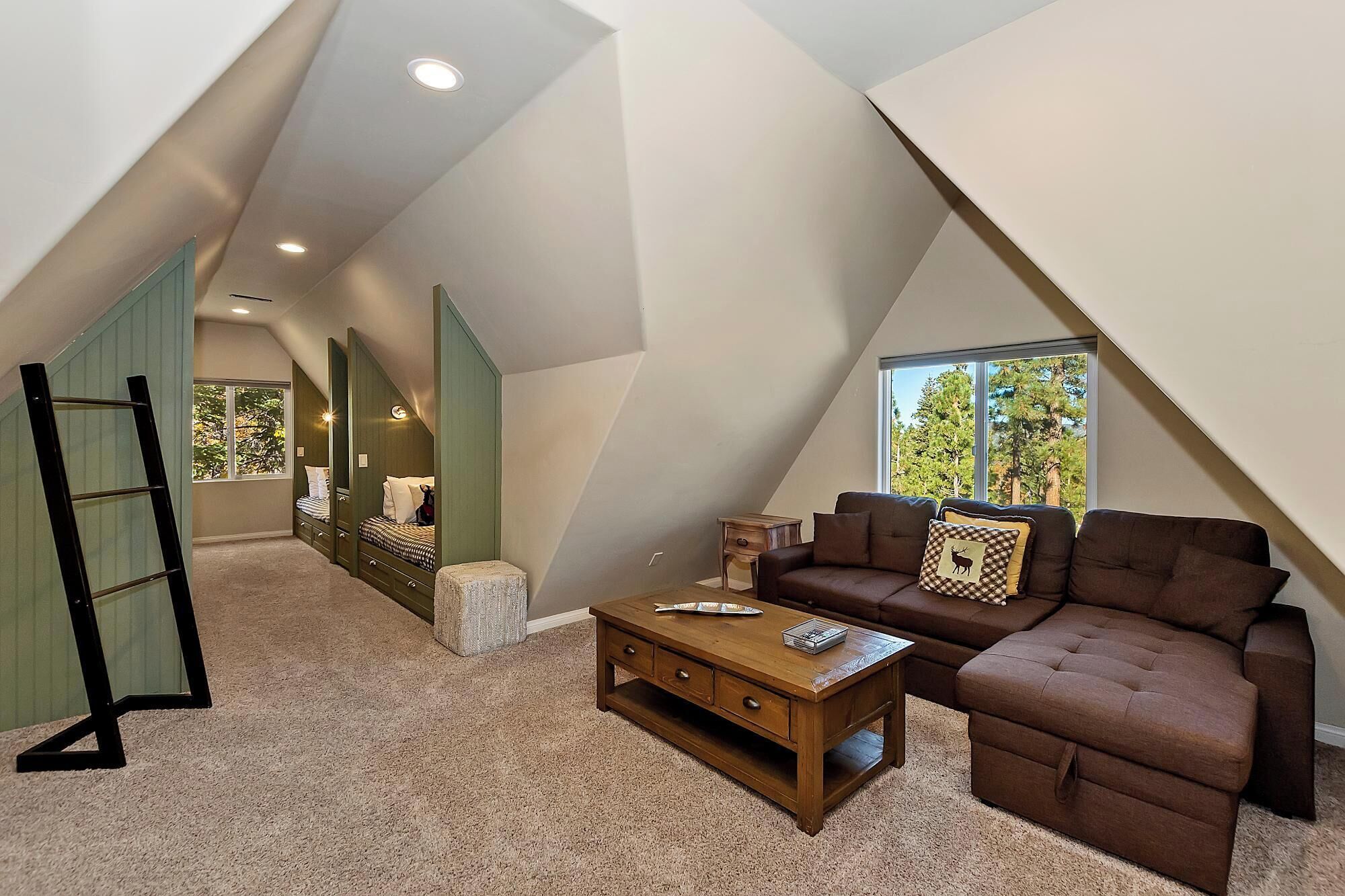 A loft-style room with a sloped ceiling, a sofa, a coffee table, and a ladder.