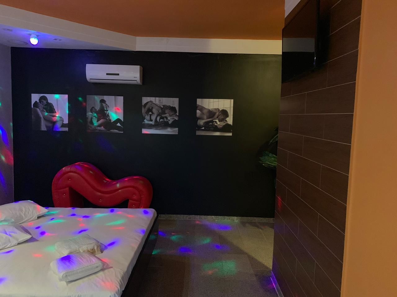 Quarto com cama, cadeira vermelha e ar condicionado fixado na parede.