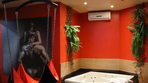 Ein Zimmer mit einer großen Badewanne, einem Hängesessel und einem Poster an der Wand.