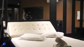 Ein modernes Hotelzimmer mit einem großen Bett, einem Hängekorbstuhl und einem blau beleuchteten Boden.