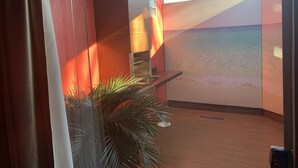 Ein Zimmer mit großem Fenster, Holzboden und einer Pflanze.