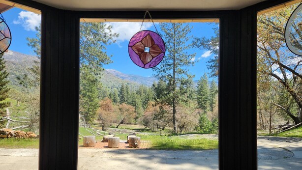 A room with a large window offering a view of a forested area with trees and a mountain in the background.