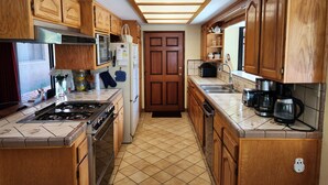 A kitchen with wooden cabinets, a gas stove, a refrigerator, a microwave, and a coffee maker.