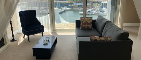 Una sala de estar con vista a un puerto deportivo y edificios.