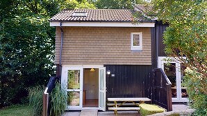 A two-story house with a tiled roof, a small window, and a door leading to a covered porch. - 24 Strawberry Hill, Tolroy Manor (Hayle)