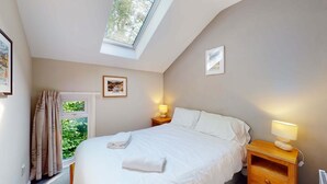 A bedroom with a skylight, a bed with white linens, two bedside lamps, and a framed picture on the wall. - 24 Strawberry Hill, Tolroy Manor (Hayle)