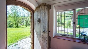 Eine rustikale Holztür mit einem Metallgriff, die zu einem Kiesweg führt.