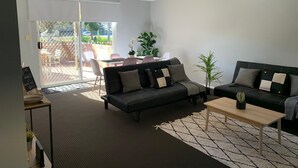 Ein modernes Wohnzimmer mit einer Couch, einem Couchtisch und einem Essbereich mit Stühlen und einem Tisch.