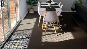 Ein Essbereich mit Tisch und Stühlen, einer Topfpflanze und einer Glastür zum Garten.
