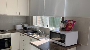 Eine moderne Küche mit weißen Schränken, einer eingebauten Mikrowelle, einem Toaster und einem Spülbecken.