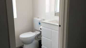 A small, clean bathroom with a toilet, sink, and mirror.