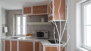Una cocina moderna con armarios de madera, encimera blanca, un fregadero, microondas y un cuenco con fruta.