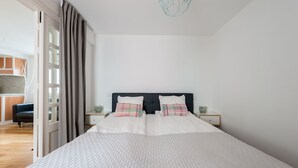 Un dormitorio moderno con una cama grande, dos mesitas de noche y vistas a una zona de cocina.