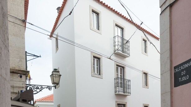 Una calle estrecha con un tranvía, un edificio blanco con balcones, y un letrero que dice "CALCADINHA DO JOGO".