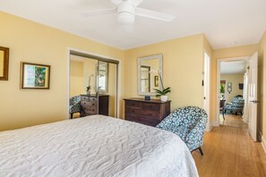 Un dormitorio con cama, cómoda, silla y ventilador de techo.