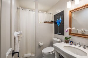 A bathroom with a shower curtain, toilet, sink, and a mirror.