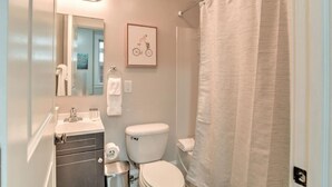 Un baño con inodoro, lavamanos y cortina de ducha.