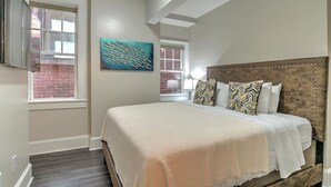 Un dormitorio con una cama grande, un muro de ladrillo y un cuadro.