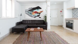 A modern living room with a sectional sofa, a coffee table, and a colorful abstract painting. - 0 Ophiussa (Lisbon)