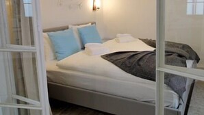 A modern bedroom with a bed, bedside tables, a wall-mounted light, and a window. - 0 Ophiussa (Lisbon)