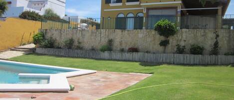 Un barrio residencial con piscina, un muro de piedra y césped bien cuidado.