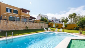 Una piscina con un muro de piedra y una zona verde.