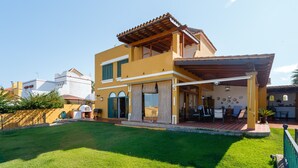 Una casa de dos pisos con un patio, una zona de barbacoa y vistas del barrio circundante.