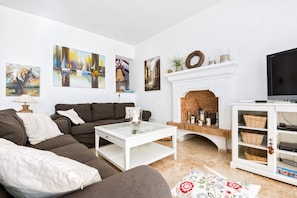 Un salon comprenant un canapé, une table basse, une cheminée et des œuvres d’art accrochées aux murs.