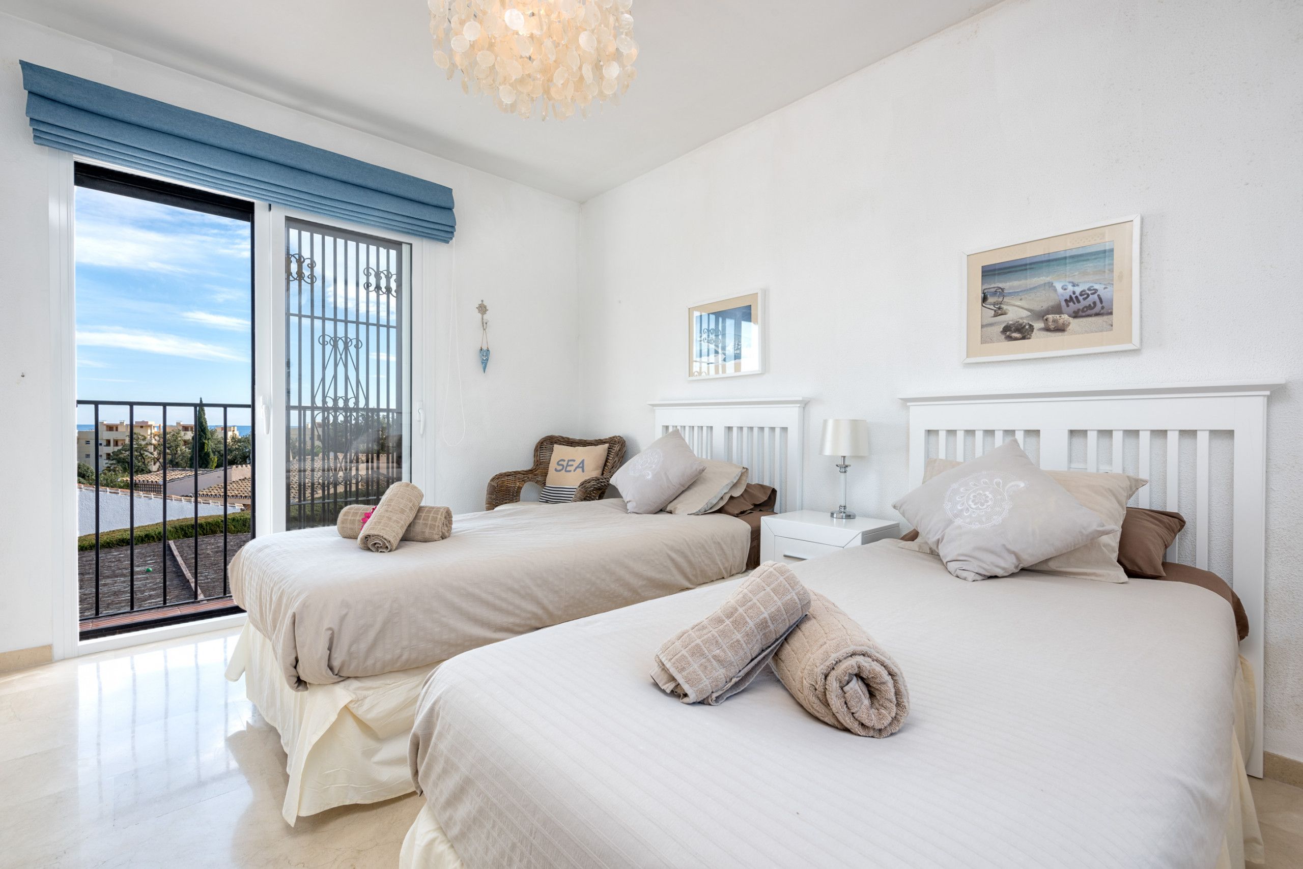 A hotel room with two beds, a balcony, a view of the city, and a painting on the wall.