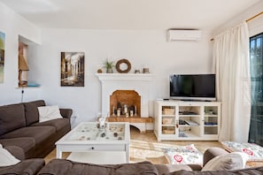 A living room with a fireplace, a television on a stand, a sofa, and a coffee table.