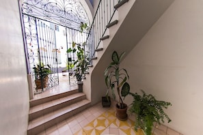Eine Wendeltreppe mit schmiedeeisernem Tor, das zu einem Balkon führt, umgeben von Kübelpflanzen.