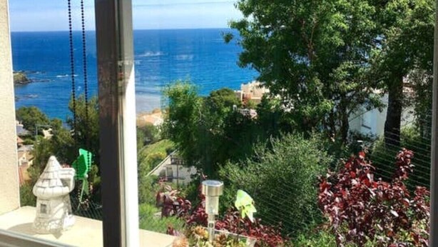 A view from a window overlooking a coastal area with trees and a clear sky. - Spectacular apartment with fantastic panoramic views (Llançà)