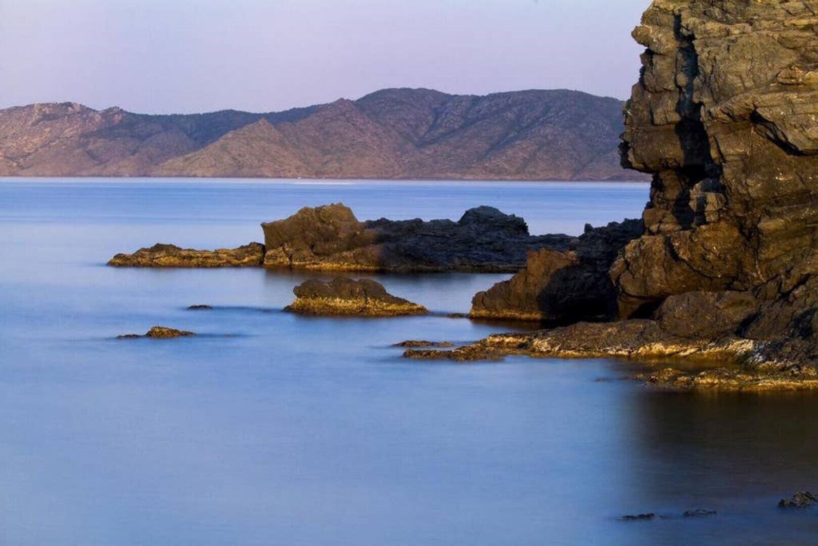 Un paisaje costero con formaciones rocosas y agua tranquila.