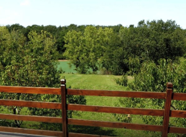 A wooden fence with a view of a green landscape and trees. - GITE LILAS (Notre-Dame-de-Sanilhac)