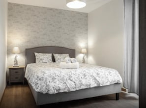 A bedroom with a bed, nightstands, and lamps.