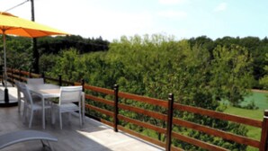 Une terrasse en bois, dotée de mobilier d’extérieur et offrant une vue sur un paysage verdoyant.