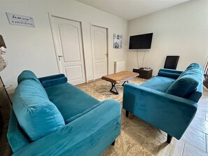 A living room with two blue sofas, a coffee table, a television, and a radiator.