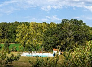 A rural landscape with a field, trees, and a small building with a red roof.
