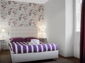 A bedroom with a bed, two bedside tables, and a window with curtains.