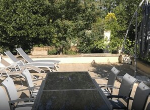 Un área de estar al aire libre con una mesa y sillas, rodeada de árboles.