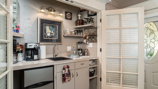 Una cocina compacta con refrigerador, cafetera y distintos utensilios de cocina.