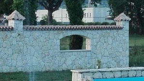 A stone wall with a small arched window and a pool with a rock feature. - Agriturismo Antica Casa Scardone (Piedimonte San Germano)