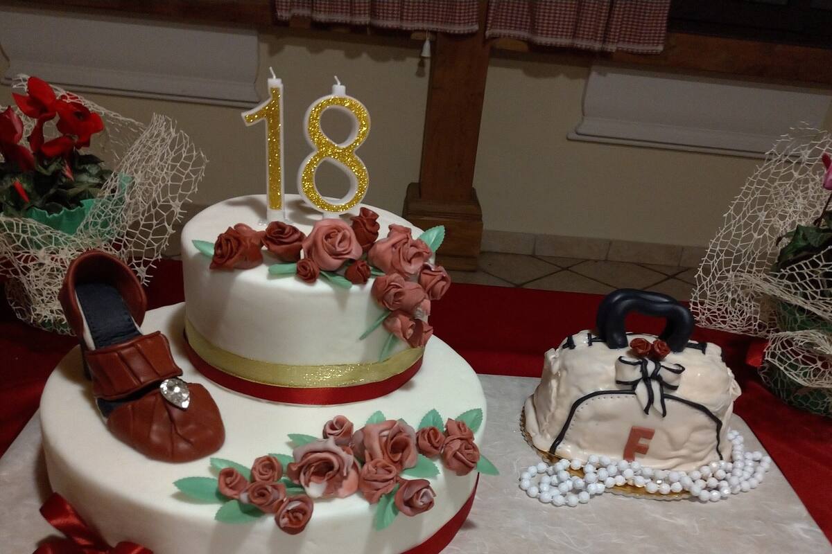 Un gâteau à deux étages, orné de dix-huit bougies, et sur lequel on peut lire, inscrit sur une nappe, les mots « AUGURI FRANCESCA ».