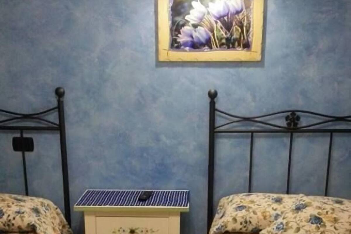 Une chambre avec deux lits, une table de chevet et un chargeur solaire fixé au mur.